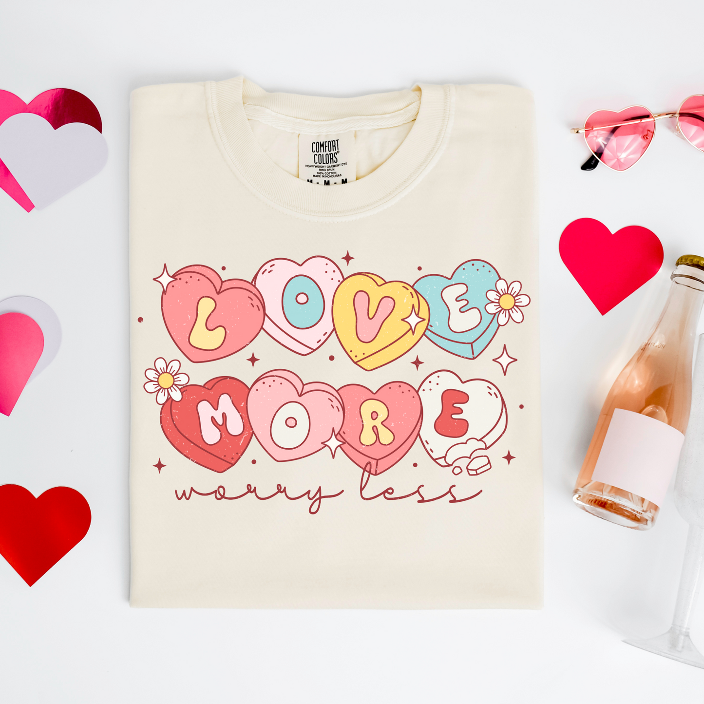 a t - shirt that says i love you more next to a bottle of wine